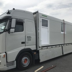 Kovinski kontejner v beli barvi, naložen na tovornjak