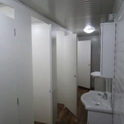 Notranjost montažnega sanitarnega kontejnerja z belimi predelnimi stenami 