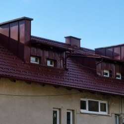 Gladka temno rdeča kritina na večstanovanjski stavbi