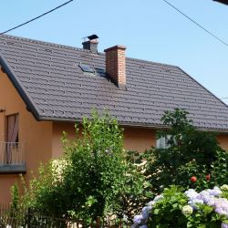 Gladka rjava strešna kritina s snegobrani na oranžni hiši