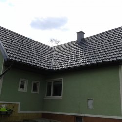 Hosekra gladka antracit strešna kritina na hiši z zeleno fasado