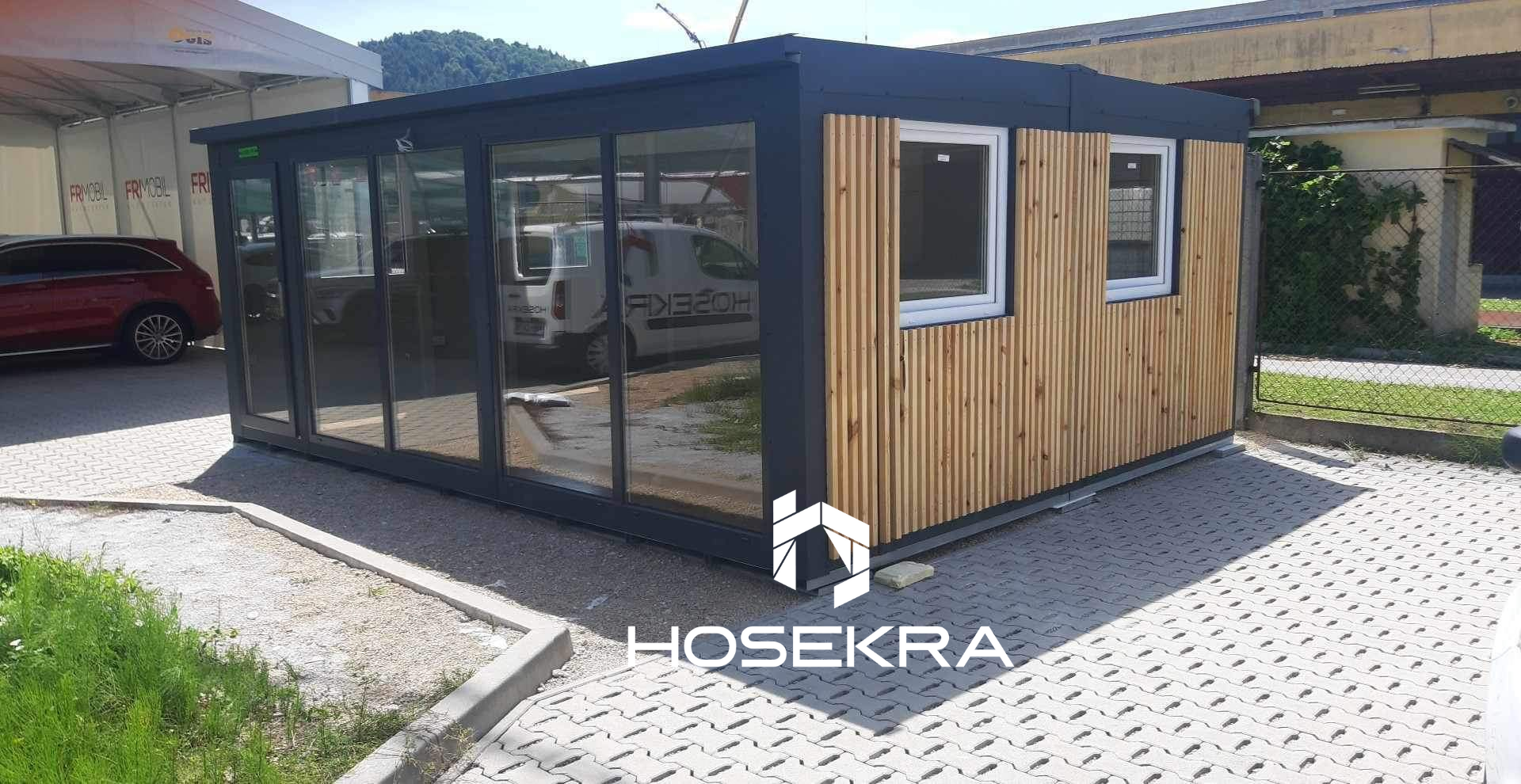 Razstavni prostor iz dveh združenih kotejnerjev Hosekra, z velikim oknom in fasado iz lamelnih desk za naraven videz
