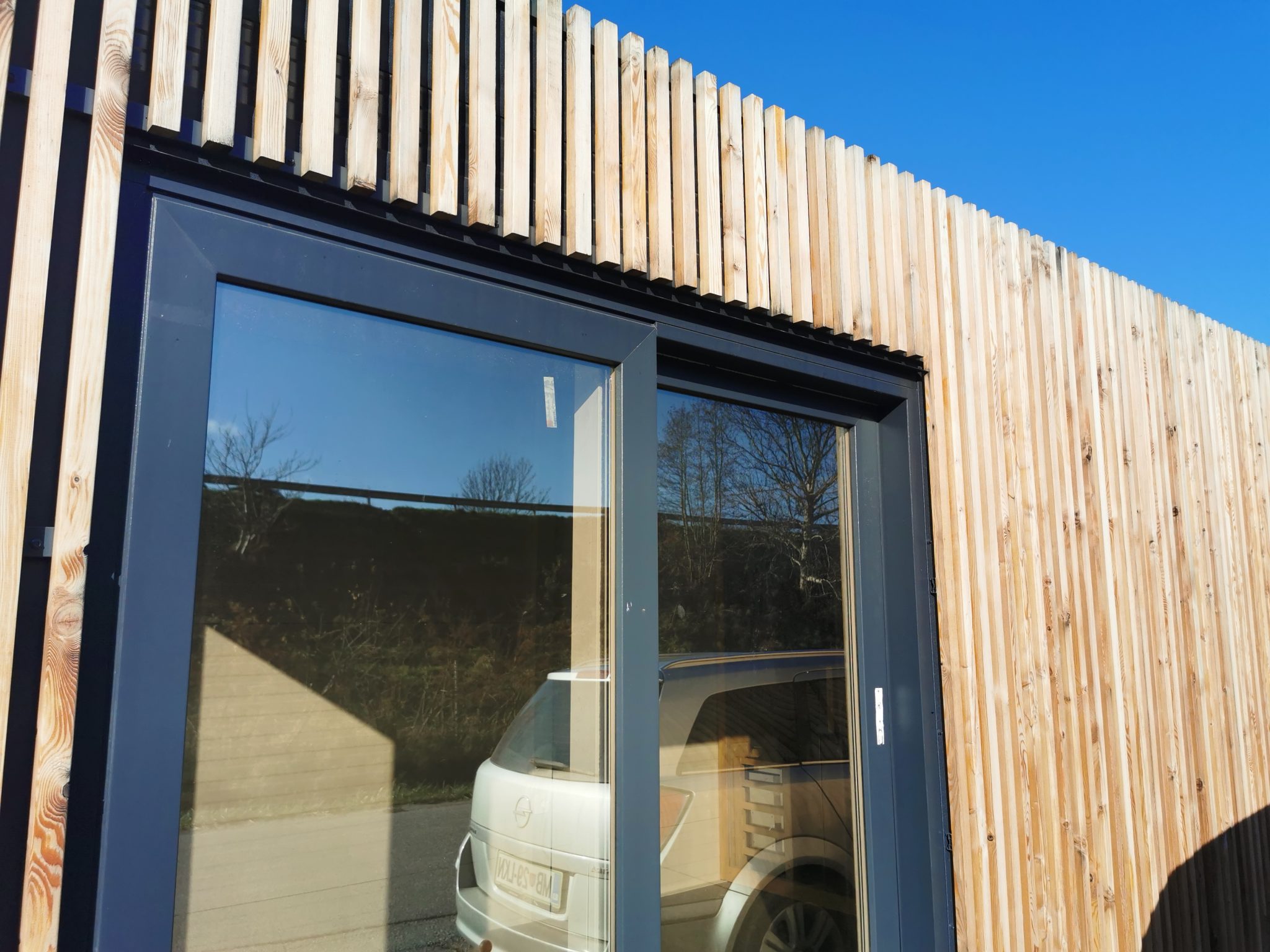 Zunanja fasada iz letvic na hosekra kontejnerju za zunanje savne, z velikimi drsnimi vrati.