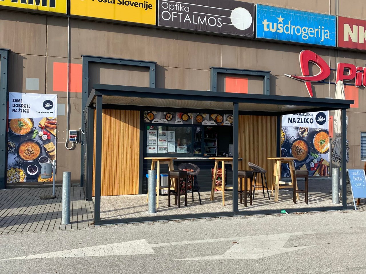 prodajni kontejnerji za lokal z leseno fasado in teraso, ob nakupovalnem središču